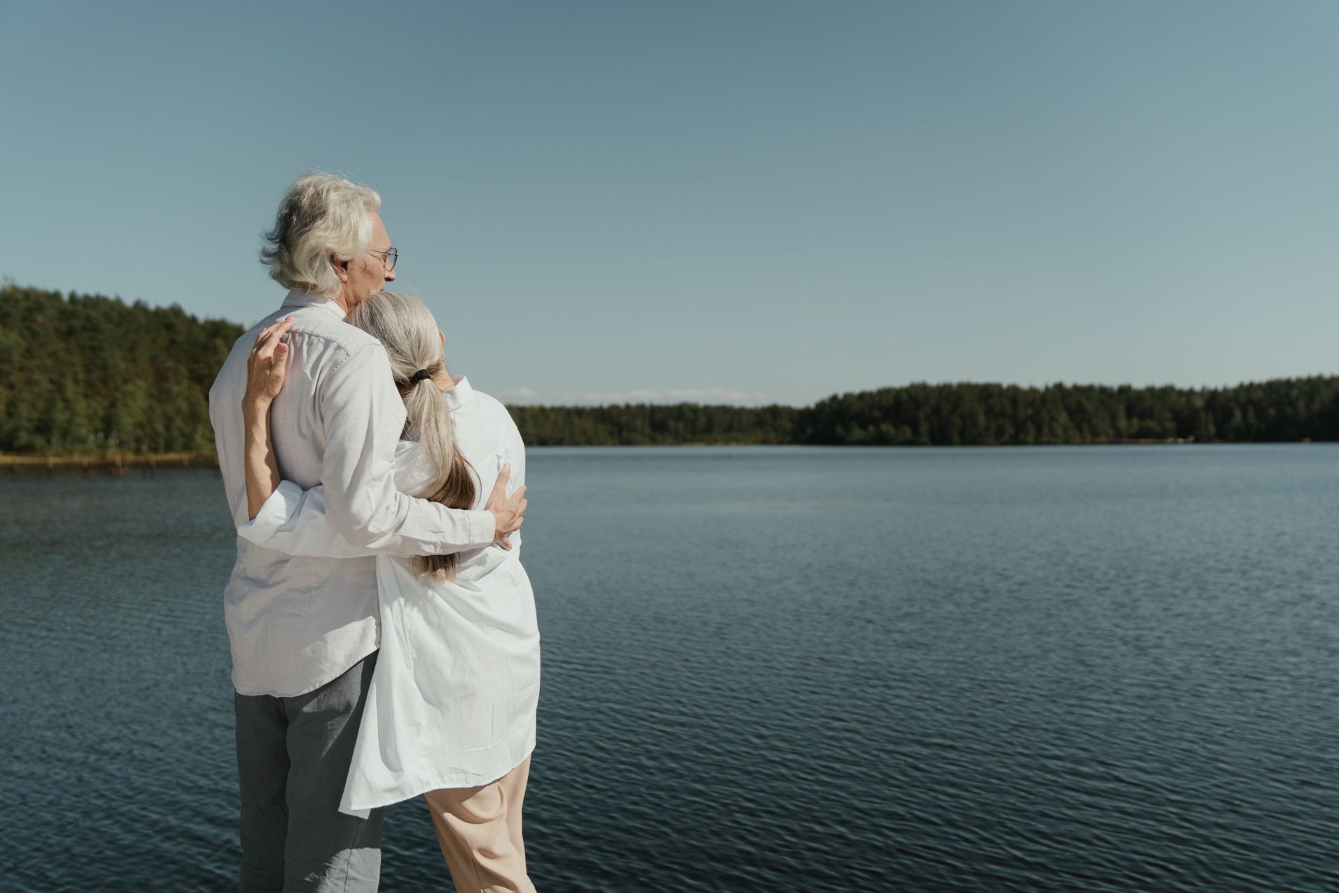An Elderly Couple Hugging near the Lake